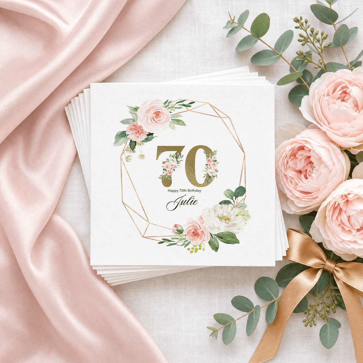 Elegant personalized 70th birthday cocktail napkins with gold-toned 70, blush watercolor roses and custom name