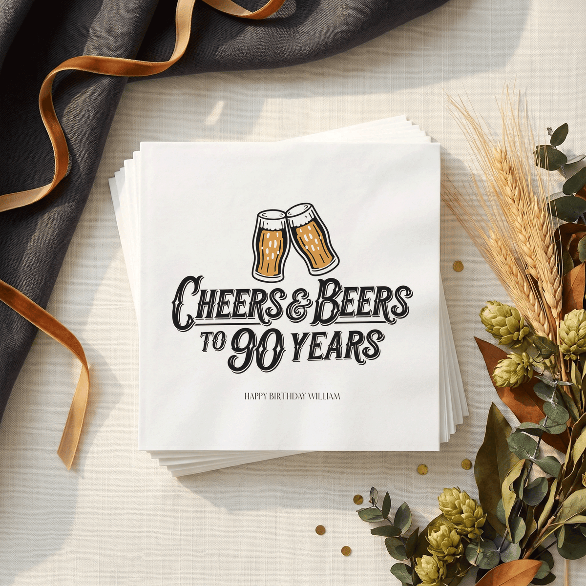 White napkin stack with “Cheers & Beers to 90 Years,” clinking beer glasses in amber and black, and a personalized birthday message below.