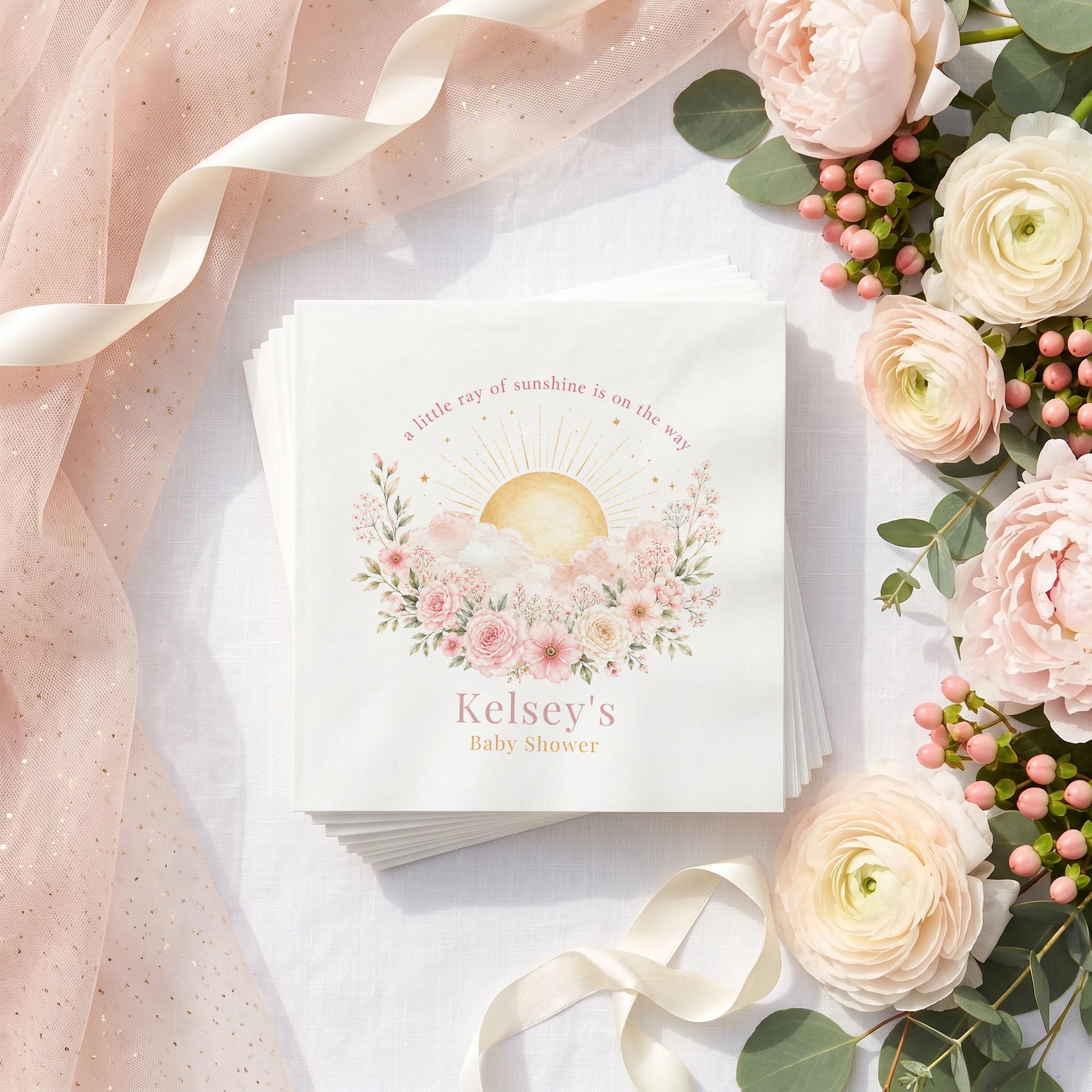 Blush pink baby shower napkin with a gold rayed sun, pink roses and clouds, personalized with a name in dusty rose