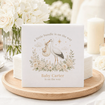 Baby shower napkins with a stork carrying a baby and text "Baby Carter is on the way."
