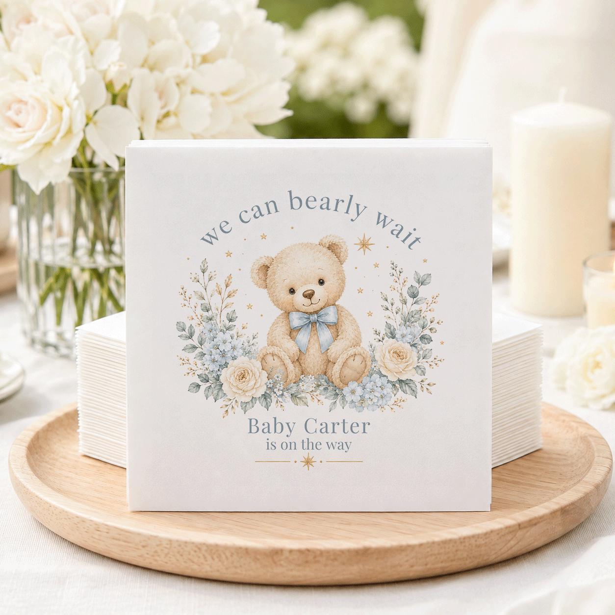 Teddy bear with blue bow surrounded by flowers and text "Baby Carter is on the way".