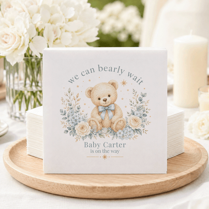 Teddy bear with blue bow surrounded by flowers and text "Baby Carter is on the way".