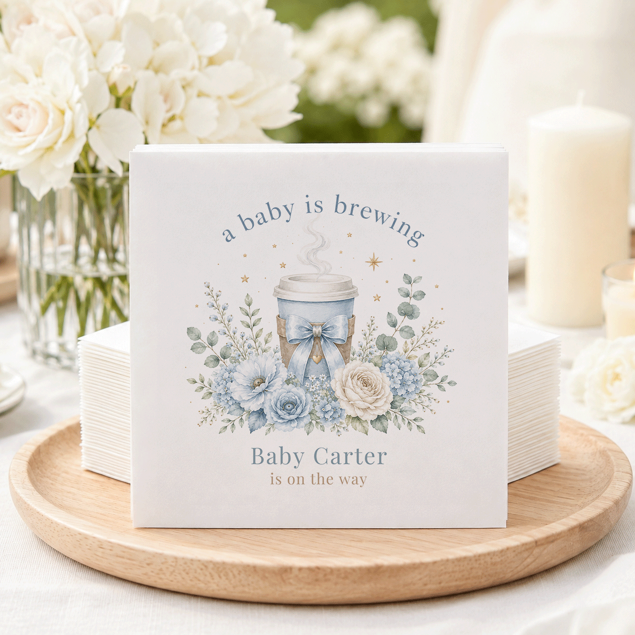 Napkins with blue floral design and text "a baby is brewing Baby Carter is on the way."