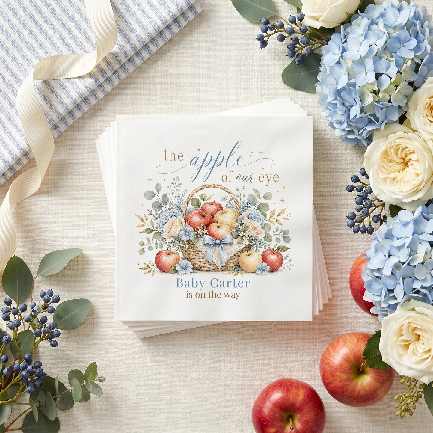Dusty blue baby shower napkin with an apple basket, blue hydrangea, cream roses and a personalized baby name
