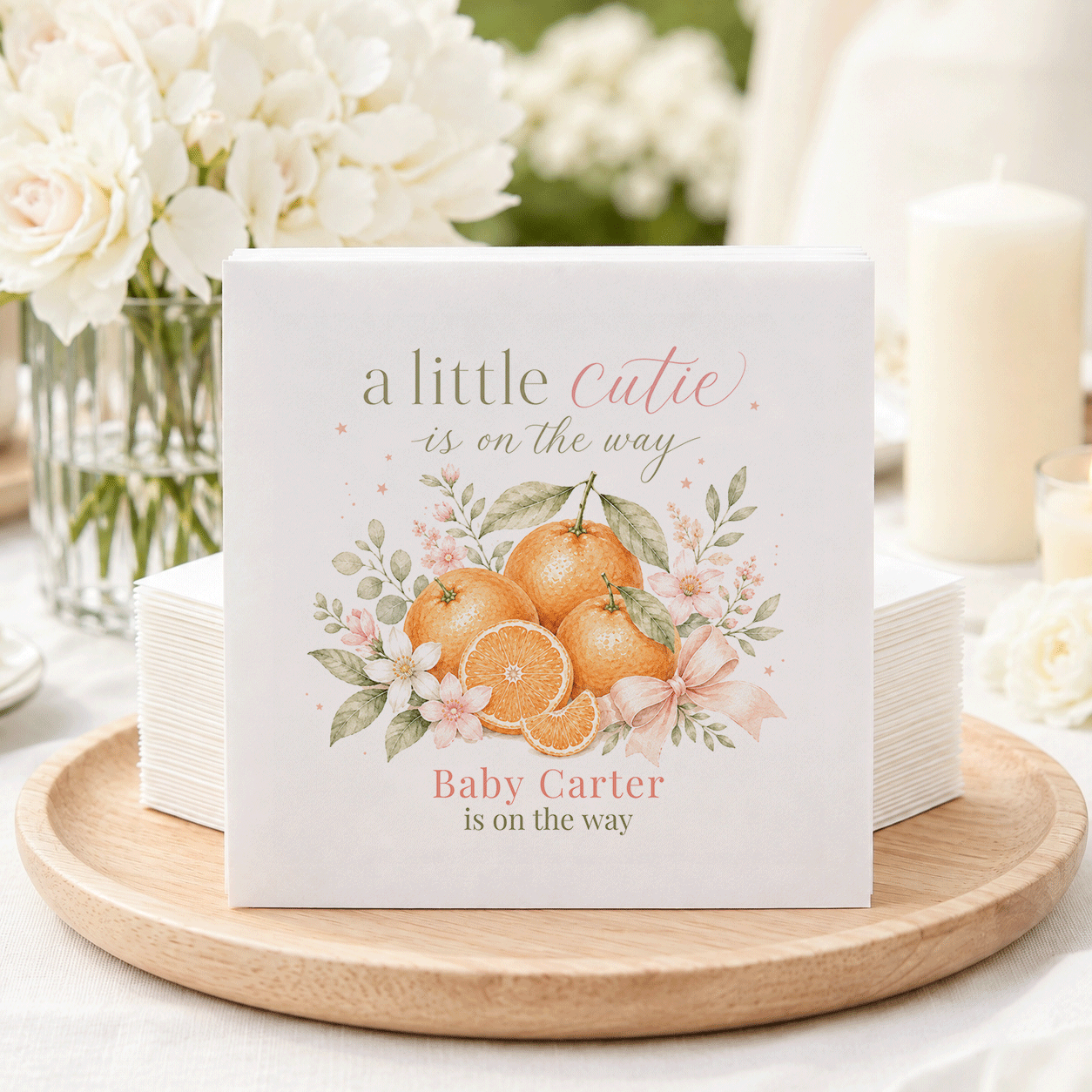 Napkins with oranges, flowers, and text "a little cutie is on the way".