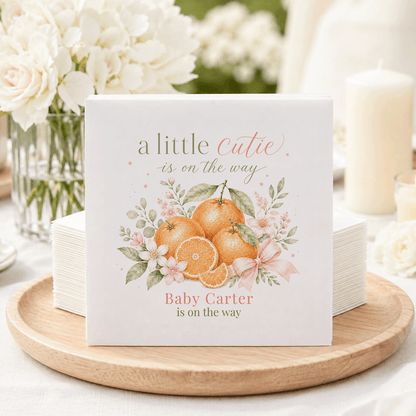 Napkins with oranges, flowers, and text "a little cutie is on the way".