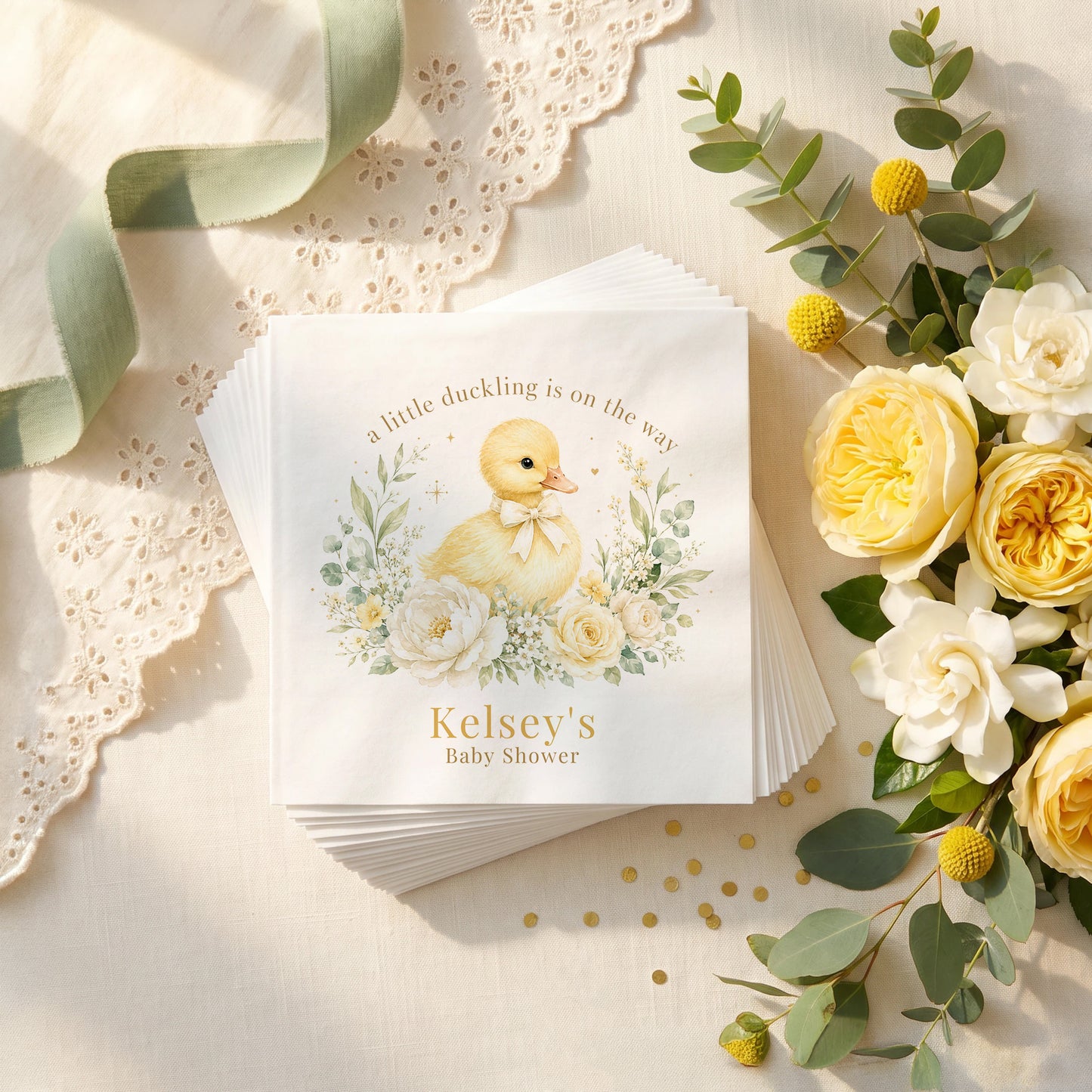 Cream and yellow baby shower napkin with a duckling in a cream bow, ivory peonies, sage leaves and a personalized name in gold
