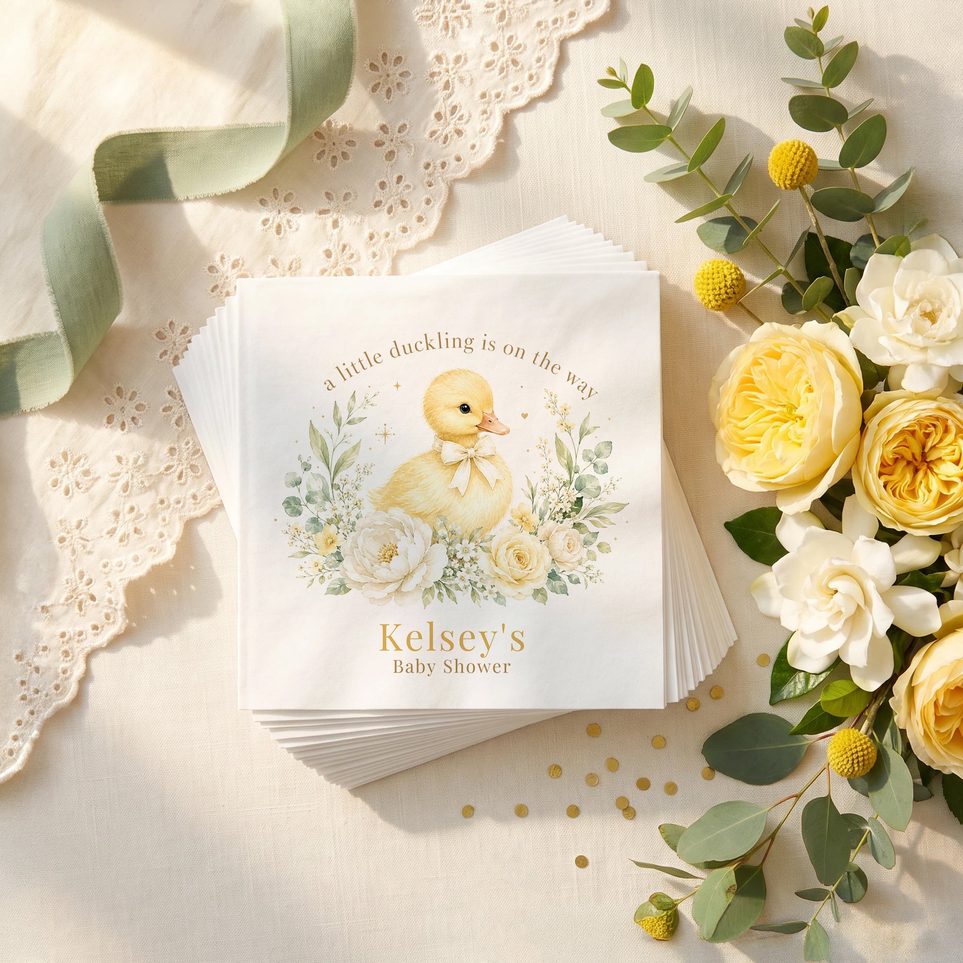 Cream and yellow baby shower napkin with a duckling in a cream bow, ivory peonies, sage leaves and a personalized name in gold
