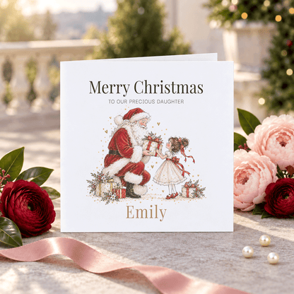Personalized daughter Christmas card featuring Santa handing a wrapped present to a little girl in a cream dress with red ribbons, with her name beneath the illustration.