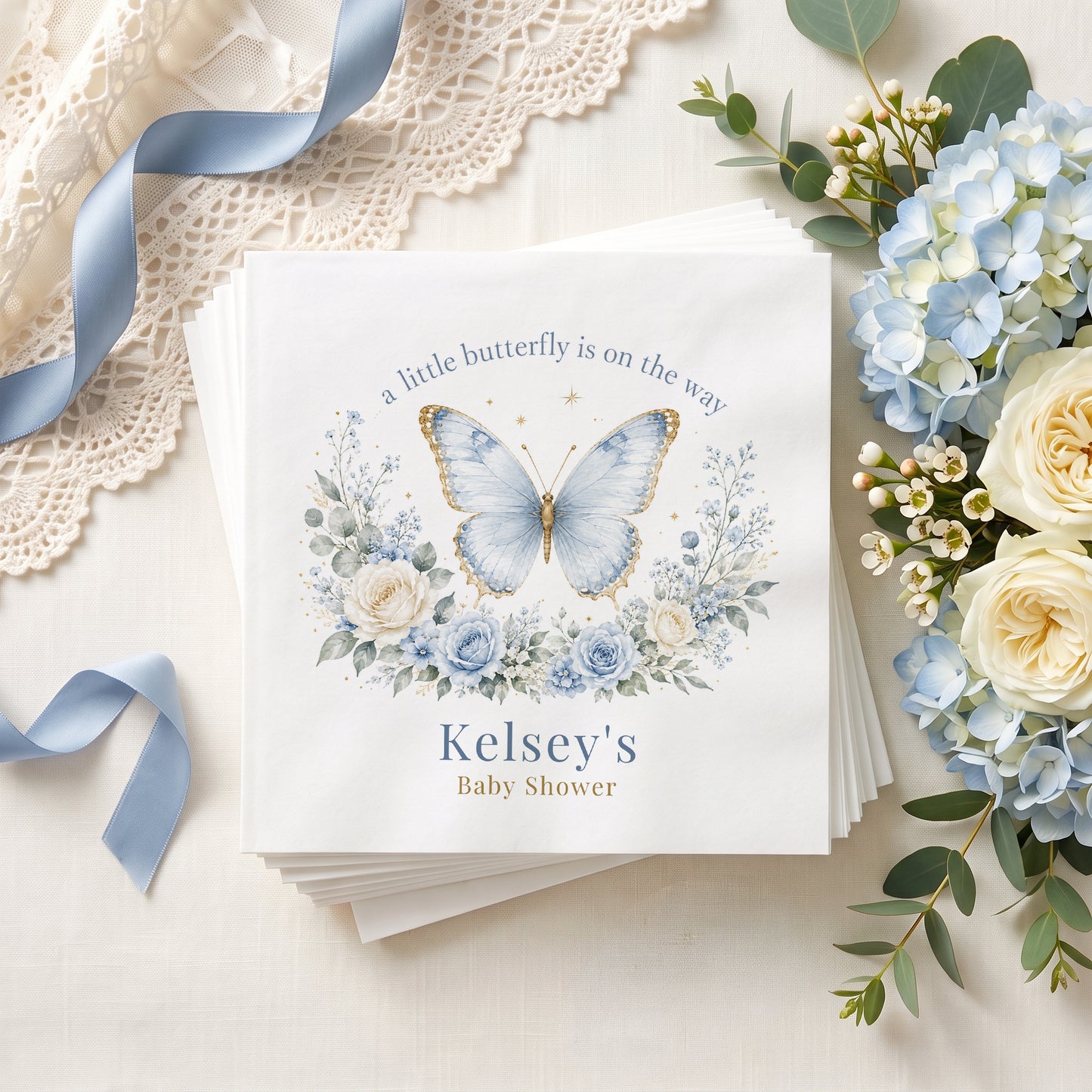 Dusty blue butterfly baby shower napkin with gold edged wings, blue roses and a personalized name in muted blue