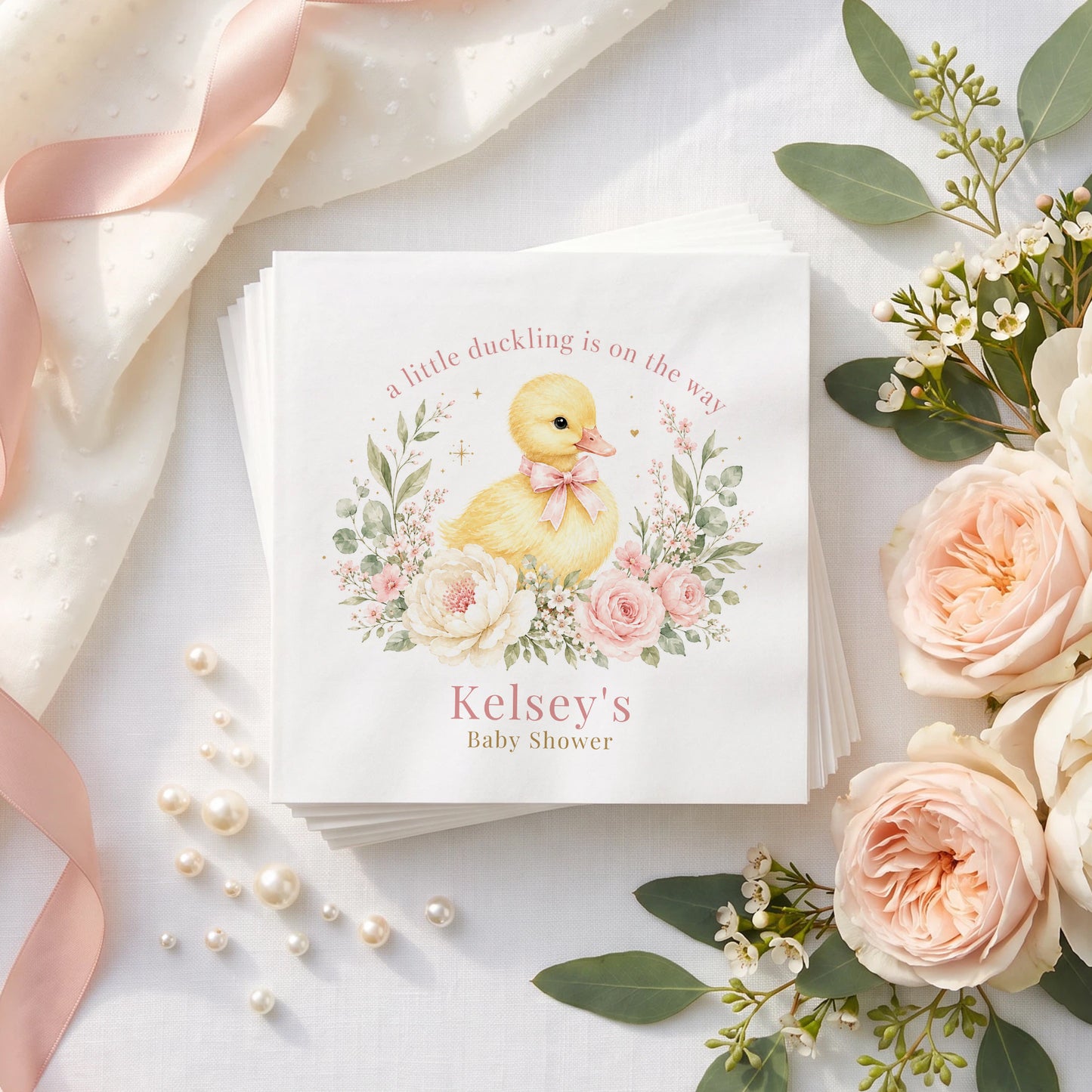 Blush pink baby shower napkin with a yellow duckling wearing a pink bow, cream peonies and a personalized name in dusty rose
