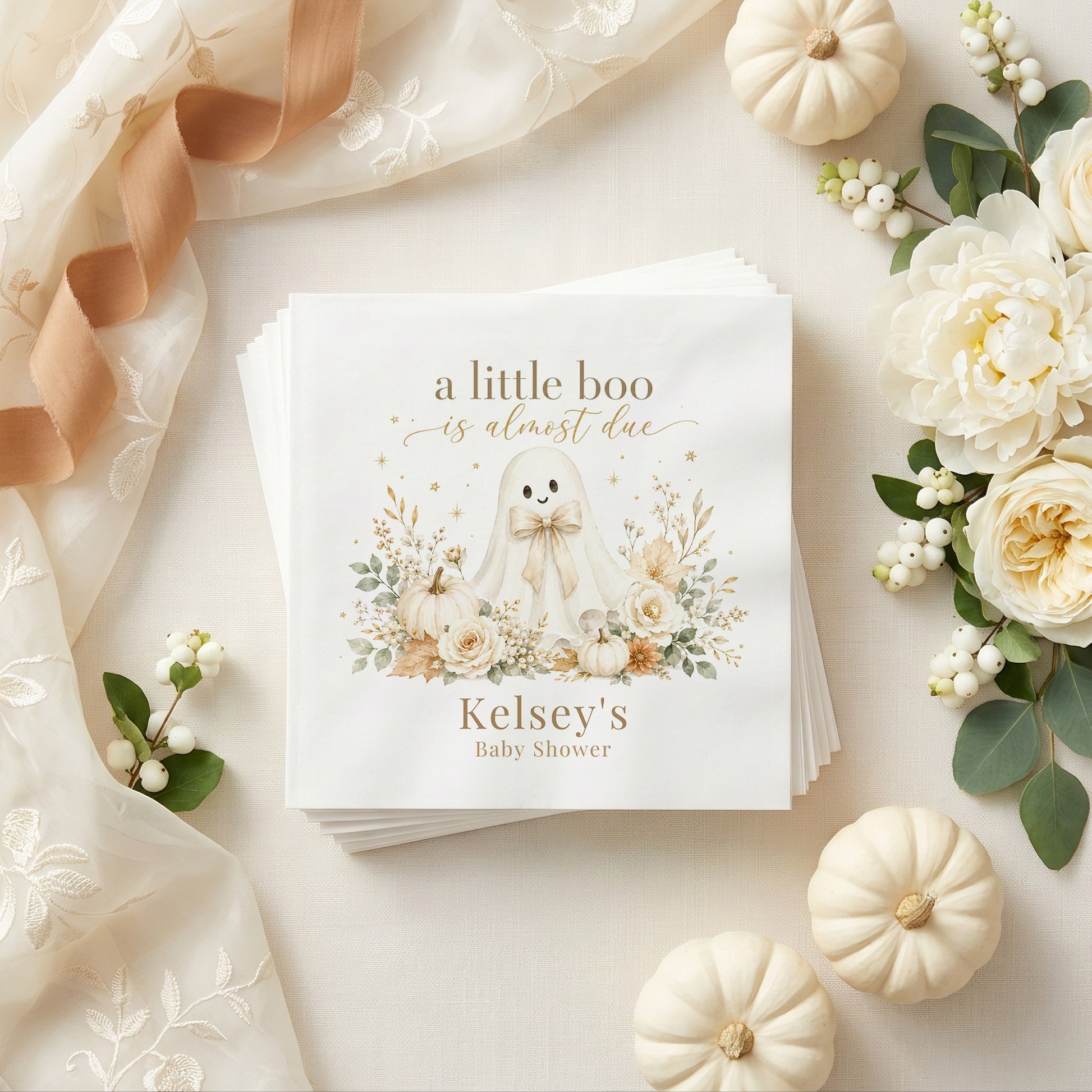 Cream and gold baby shower napkin with a ghost, white pumpkins, ivory roses, dried leaves and a personalized name