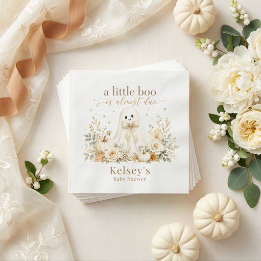 Cream and gold baby shower napkin with a ghost, white pumpkins, ivory roses, dried leaves and a personalized name